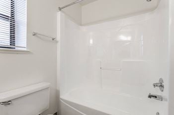 A white bathroom with a tub, shower, and toilet